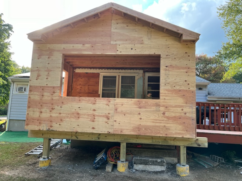 Home addition under construction with plywood sheathing and framed window opening