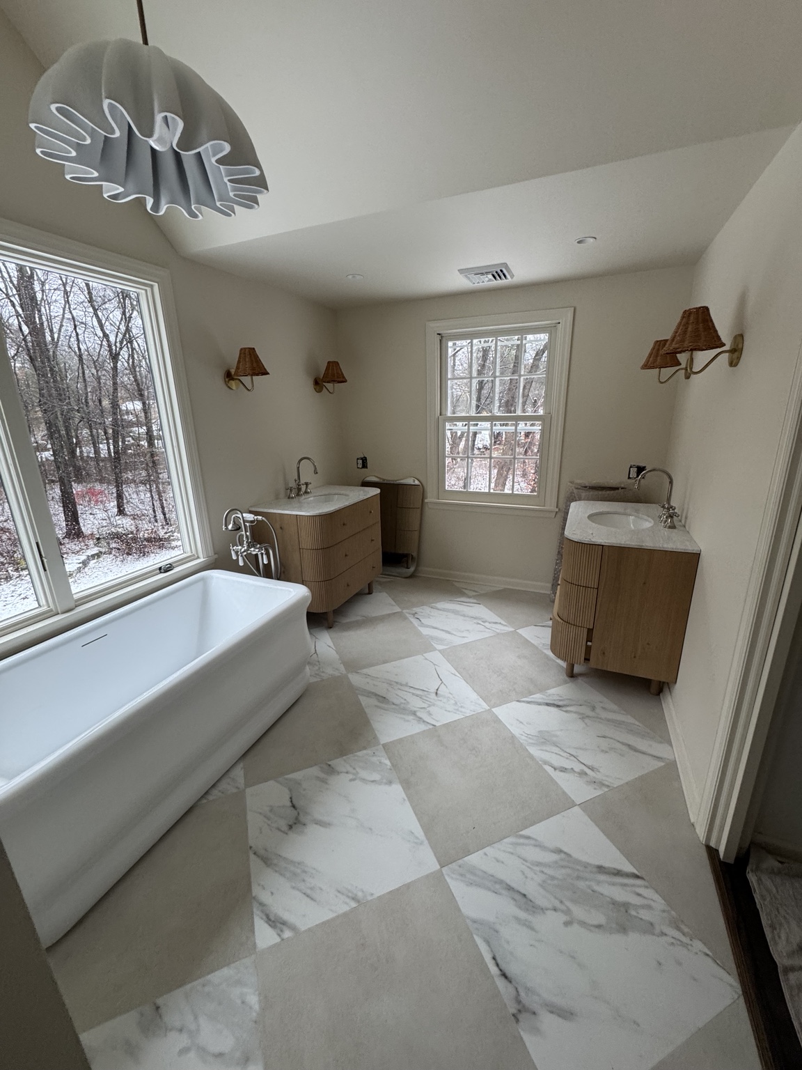 Bathroom remodeling with freestanding bathtub, custom wood vanities and marble-look tile floor